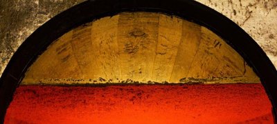 Die Kombination aus roter Flüssigkeit und goldenem Holzrand erzeugt einen faszinierenden Kontrast, der die Sinne anspricht.