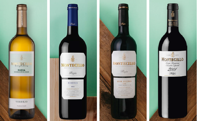 Vier Flaschen Wein stehen auf einem hellgrünen Hintergrund, jede mit einem eleganten Etikett und unterschiedlichen Farben.