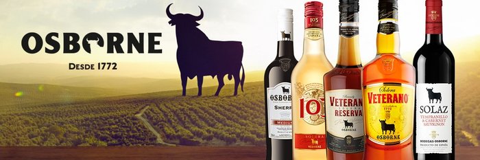 Im Vordergrund stehen mehrere Osborne-Flaschen, während im Hintergrund sanfte Hügel und ein Sonnenuntergang sichtbar sind.