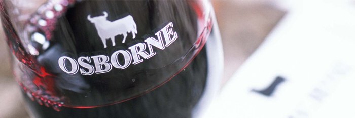 Nahaufnahme eines Weinglases mit rotem Wein, das den markanten Schriftzug 'OSBORNE' und ein Stier-Symbol zeigt.