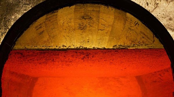 Die Kombination aus roter Flüssigkeit und goldenem Holzrand erzeugt einen faszinierenden Kontrast, der die Sinne anspricht.