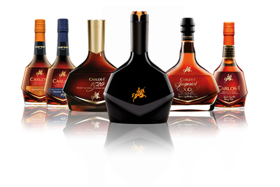 Sechs Flaschen edlen Brandys stehen auf einem spiegelnden Tisch, jede mit einzigartigem Design und Etikett, in warmen Farbtönen.